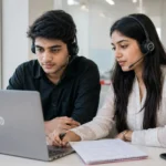 A young Indian fresher in professional attire sitting at a desk with a headset, preparing for a Concentrix BPO interview with notes visible beside a laptop.