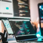 Laptop and smartphone displaying data analytics dashboards and code, representing the journey to becoming a Data Analyst in India.