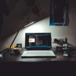 Software engineering workspace with a laptop, coding environment, desk lamp, and coffee mug, representing the path to becoming a Software Engineer in India.