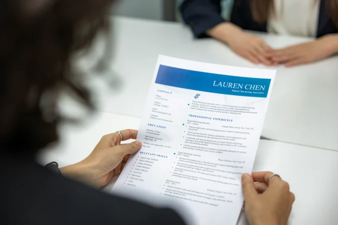 Indian fresher reviewing a professionally formatted resume on a modern office desk with laptop, notebook, and coffee, representing resume writing for candidates with no work experience.