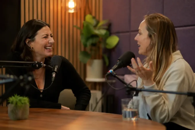 Two women having a confident, engaged conversation in a podcast studio